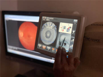 A technician using a TRC-NW400 to capture a retinal image. The technician is aligning the lens of the instrument with the patient’s pupil using the touchscreen.