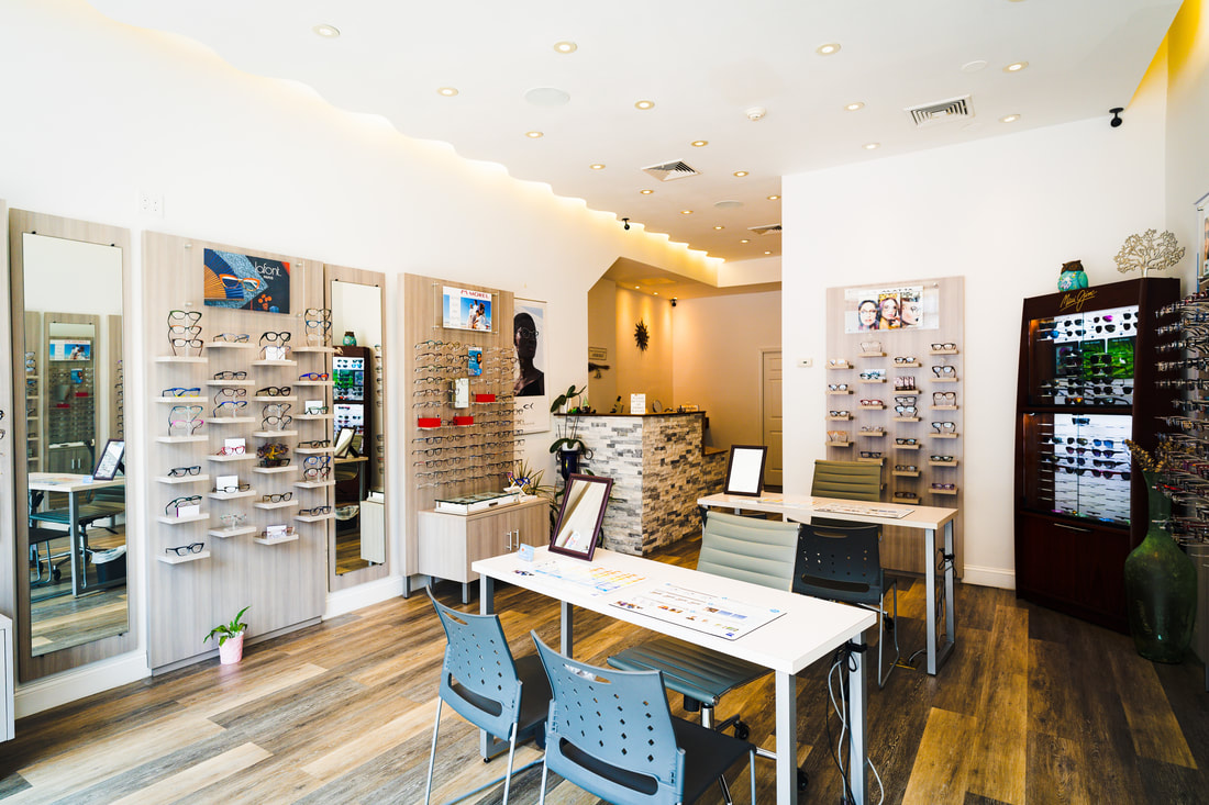 A well-lit showroom with tall mirrors, showcasing designer frames from Italy, France, Japan, and South Korea. The showroom features a beautiful stone-faced receptionist desk and is located at 44 North Main Street, Port Chester, NY. Port Chester Eye Care